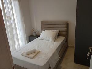 a bedroom with a bed with white sheets and a window at GN summer guest house P in Leptokarya
