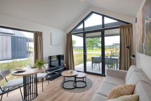 a living room with a couch and tables and a tv at Resort Boschmolenplas in Heel