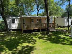 a mobile home with a deck and trees at Mobil home B1Bis La Pointe LB in Capbreton +5 photos
