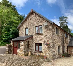 una casa in pietra con una porta rossa di Riscombe Farm Cottages a Exford