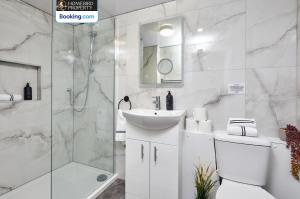 a white bathroom with a sink and a shower at Beautiful 3BDR House By Homebird Property Management Short Lets & Serviced Accommodation Leeds With Free Parking & Free WiFi in Leeds