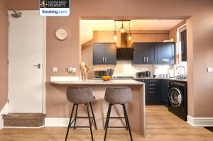 a kitchen with two bar stools at a counter at Beautiful 3BDR House By Homebird Property Management Short Lets & Serviced Accommodation Leeds With Free Parking & Free WiFi in Leeds +55 photos