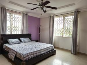 Un dormitorio con una cama y un ventilador de techo. en Kadny Villa, en Accra