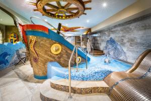 a large indoor pool with a water slide at Spa Hotel Podlesí - Walldorf a Pohádková vesnička in Podlesí
