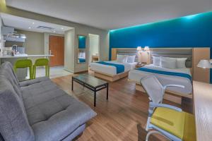 a hotel room with two beds and a couch at City Express by Marriott Playa del Carmen in Playa del Carmen