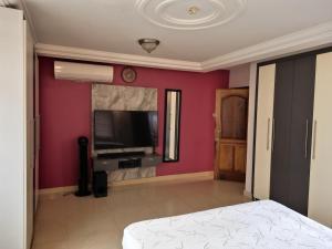 Un dormitorio con paredes rosas y un televisor de pantalla plana. en Kadny Villa, en Accra