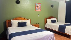 two beds in a room with green walls at Hotel La Cascada Oaxaca in Oaxaca City