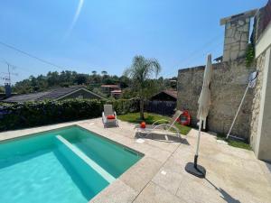 a swimming pool with two chairs and an umbrella at Casa da Galheira in Vilela