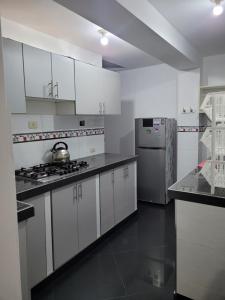 eine Küche mit weißen Schränken und einem Edelstahlkühlschrank in der Unterkunft Departamento cerca del aeropuerto in Lima
