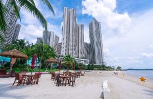 a beach with chairs and tables and tall buildings at 3BR Luxury Seaview Suite Danga Bay Legoland in Johor Bahru