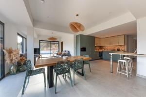 Una cocina y un comedor con mesa y sillas de madera. en NOUVEAU ! Maison de standing avec piscine et climatisation entre mer et montagnes, en Albitreccia