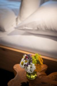 a vase of flowers on a table next to a bed at Alma Hotel Oberstdorf in Oberstdorf