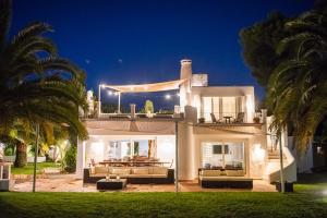 a large white house with couches and palm trees at Villa 8br, Sea Views, Walk To The Beach, Pool in Santa Eularia des Riu