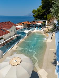 a swimming pool with an umbrella and the ocean at Villa Višnja Prestige in Brela