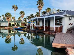a house with a dock next to a body of water at The Marina House in Jeffreys Bay