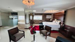 a bedroom with a bed and two chairs and a bathroom at SHELTON PALACE HOTEL in Paranavaí