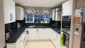 a kitchen with white cabinets and a black counter top at Smile House Doncaster in Doncaster