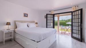 a white bedroom with a bed and a balcony at Vinha da Quinta in Sintra