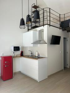 cocina con armarios blancos y nevera roja en Puerta de los Castañares A, en Constantina