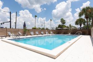 a large swimming pool with chairs and a fence at The Vietta Hotel in Kissimmee