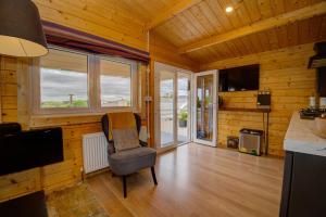 a room with a chair and a television in a room at Luxury Log Cabin with Private Hot Tub & Sea Views in Letterkenny