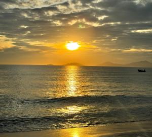 a sunset on the beach with a boat in the water at Hestia HaMy Beach House in Hoi An +67 photos