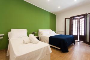 a room with two beds and a green wall at Verdirooms158 in Castellammare del Golfo