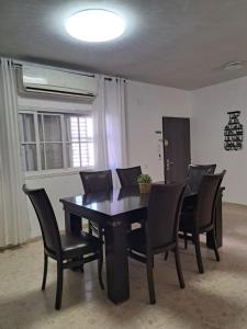 a black dining room table with black chairs and a window at דירה בעמק in Bet Sheʼan