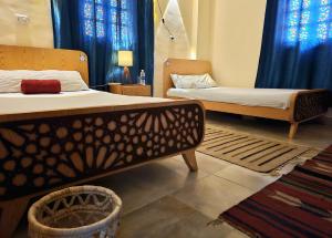 a bedroom with two beds with blue curtains at Bedouin Hostel- دار البدوي in Dahab