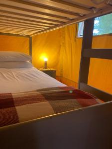 a bedroom with a bed with a blanket on it at Cefn Crib Safari Tent in Machynlleth