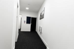 a hallway with white walls and black carpet at Credit Corner Studio in Brierley Hill +19 photos