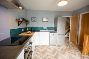 a kitchen with white appliances and blue tiles at Puffin Cottage in Beaumaris