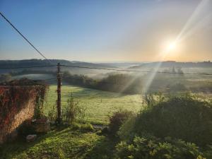 a misty field with the sun shining on the horizon at la ferme du Planeau in Montchenu