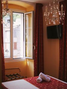 a bedroom with a bed and a window and a television at Hôtel U Palazzu & Spa - Centre du village in Venaco