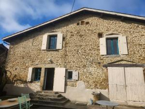 an old stone house with white windows and a table at la ferme du Planeau in Montchenu