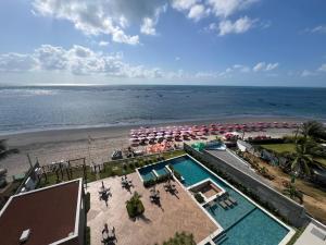 eine Luftaufnahme eines Strandes mit Sonnenschirmen und einem Swimmingpool in der Unterkunft Mirante Porto Galinhas beira-mar in Porto De Galinhas