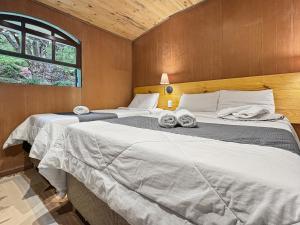 two twin beds in a room with a window at 1 suíte Jacuzzi Lareira Churrasqueira in Campos do Jordão