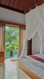 a bedroom with a canopy bed and a large window at Villa De Cupit Ubud Gianyar Bali in Ubud +17 photos