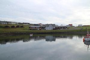 a small boat in a body of water with houses at Framtid Camping Lodging Barrels in Djúpivogur