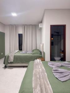 a bedroom with two beds and a toilet in it at Casa Green Boa Vista in Barreirinhas