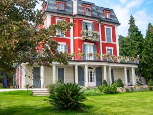 La Villa di Elena في فيربانيا: منزل أحمر كبير ذو شرفة على حديقة