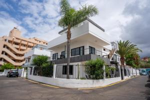 un bâtiment blanc avec un palmier devant dans l'établissement Centric and bright apartment - Puerto de La Cruz, à Puerto de la Cruz