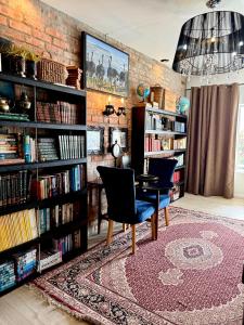 a library with two chairs and a table and bookshelves at Royal Library Room in Mossel Bay