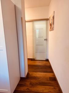 a hallway with a white door and a wooden floor at Enns Sleep Self Check In in Enns