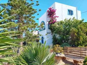 a white house with plants and a wooden bench at Naxian Sofias garden in Naxos Chora