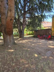 two red chairs and a table under a tree at La Hora Feliz - Metro Sesto Rondo' in Sesto San Giovanni