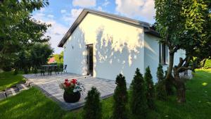 a small white house with a patio in a yard at Domki w Winnicy - Świętokrzyska Winnica Knapów in Krzczonowice