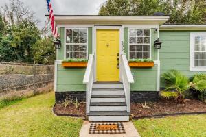 a green house with a yellow door and stairs at Sunny Midtown Cottage- Midtown Mobile in Mobile