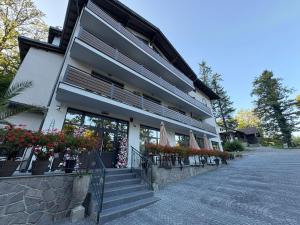 a building with potted plants and flowers in front of it at Vila Intre Lacuri in Sovata