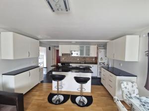 a kitchen with white cabinets and black counter stools at HOLIDAY NEST Family Guest House 80m2 - Mysigt gästhus med två sovrum i Höör in Höör